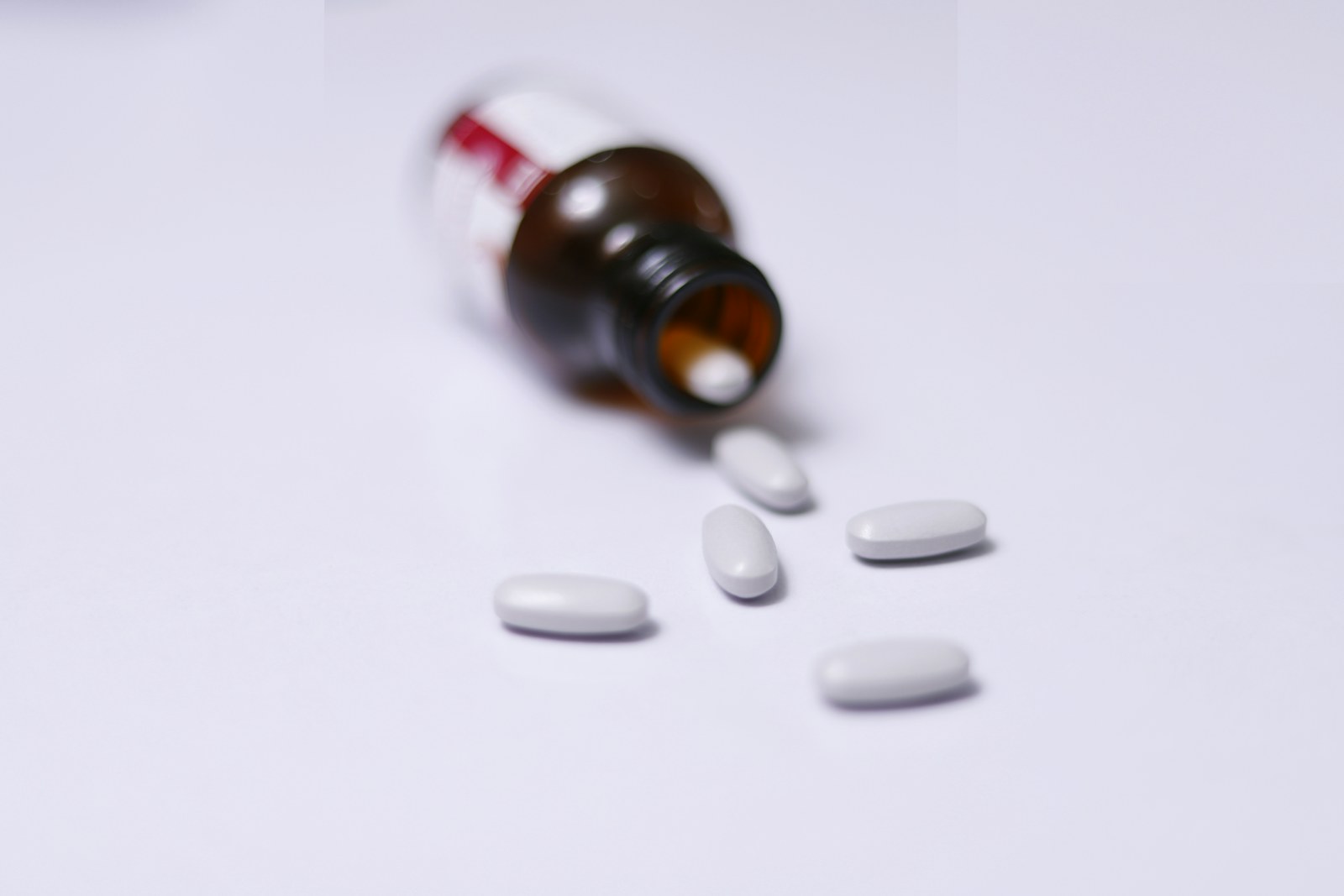 An unmarked medicine bottle with white tablets on a plain surface